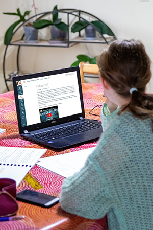 Girl with Blue sweater studying on a laptop computer
