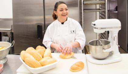A culinary student cutting bread