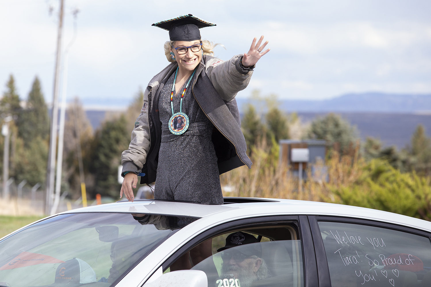 Tiara Bartlett waves to faculty from her car at the graduation parade