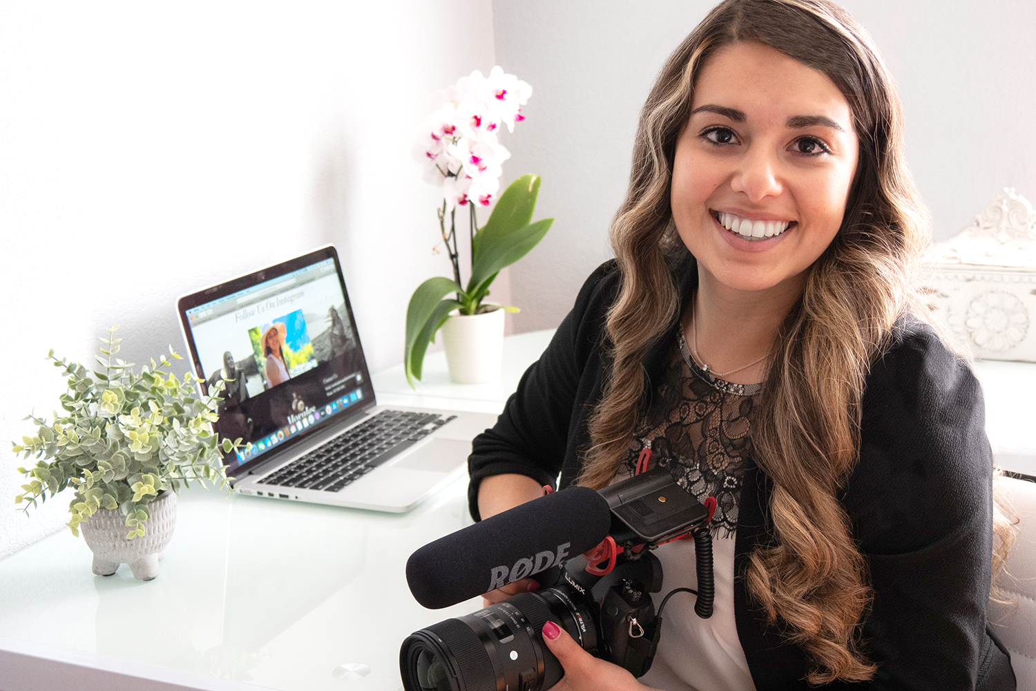 CWC alumna Abbey Morales sits at a white desk with her DSLR camera