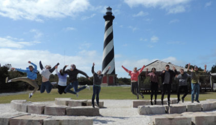 The Entrada club jumping in front of a lighthouse in North Carolina