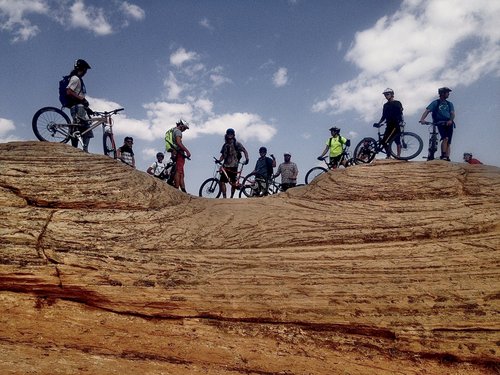 Photo of people riding mountain bikes on top of a rocky cliff